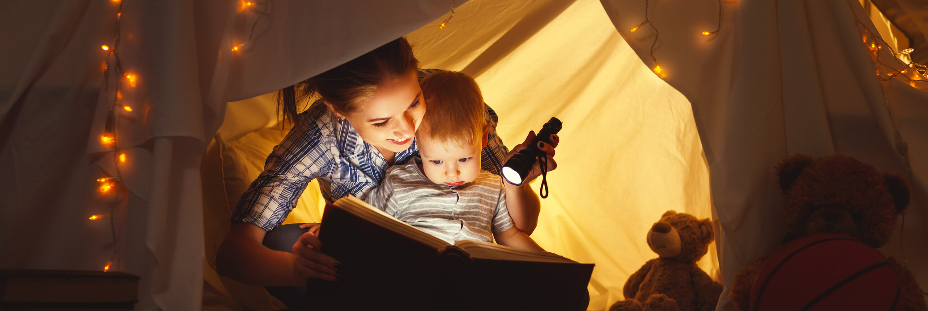 Reading a book to a baby in a tent