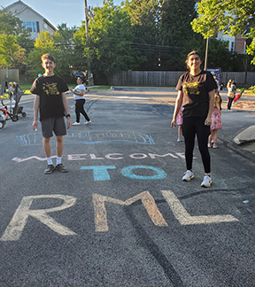 Smiling teens standing next to chalk drawing that says Welcome to RML