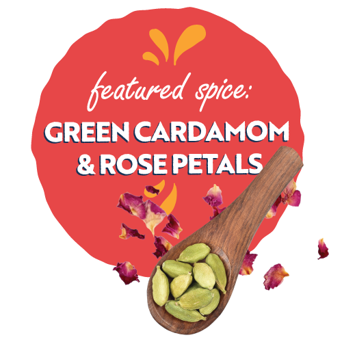 green cardamom pods on a spoon with rose petals scattered