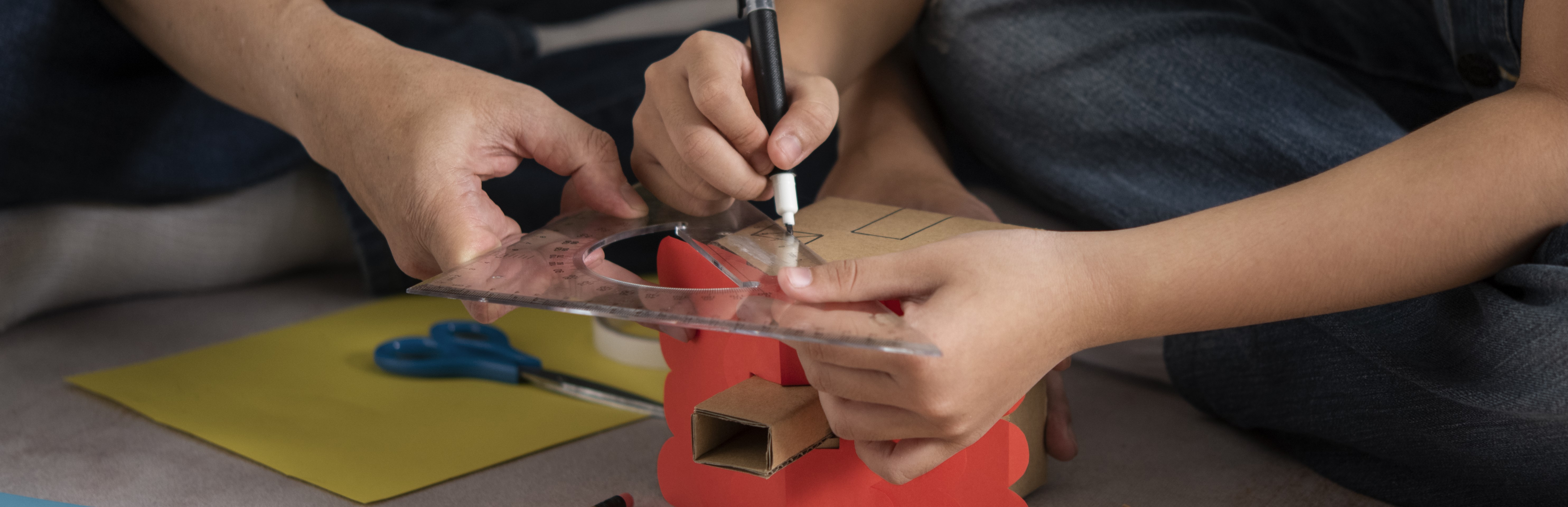 Close up of kids hands building a cardboard house