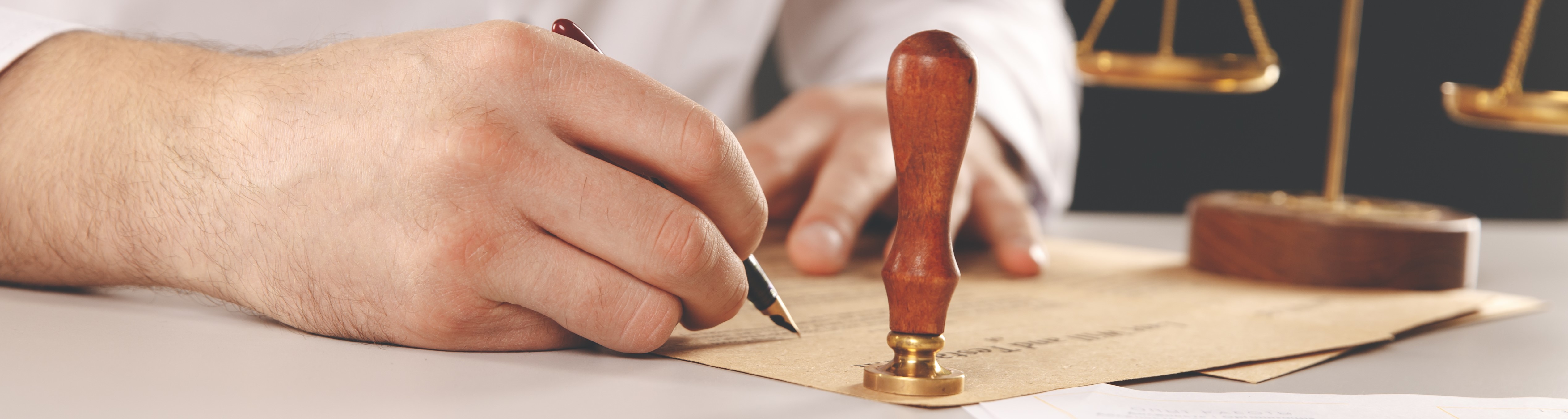 Hand signing documents with a notarty stamp next to it.